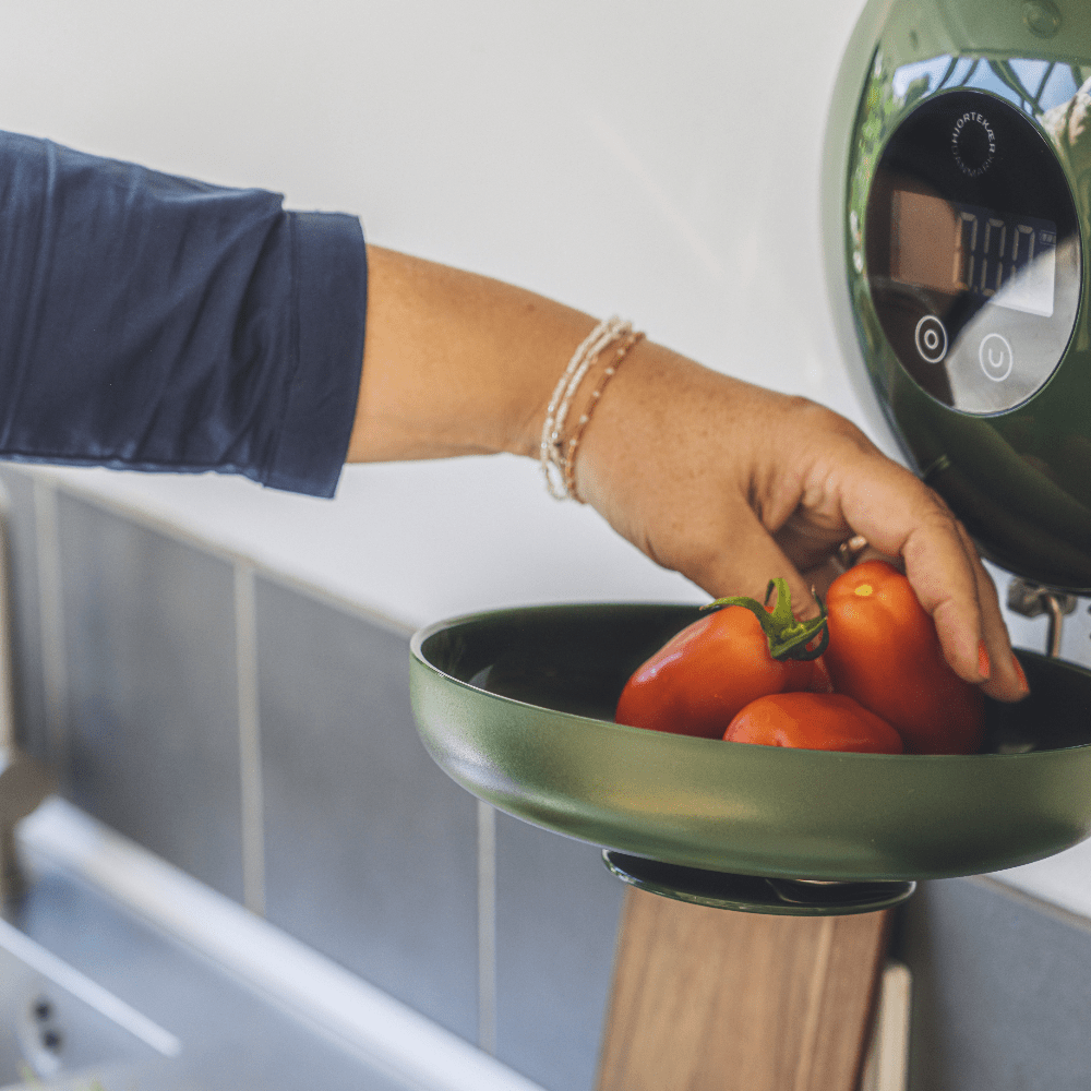 Wally Wand-Küchenwaage mit grüner Schüssel, Hand wiegt Tomaten im Alltagseinsatz
